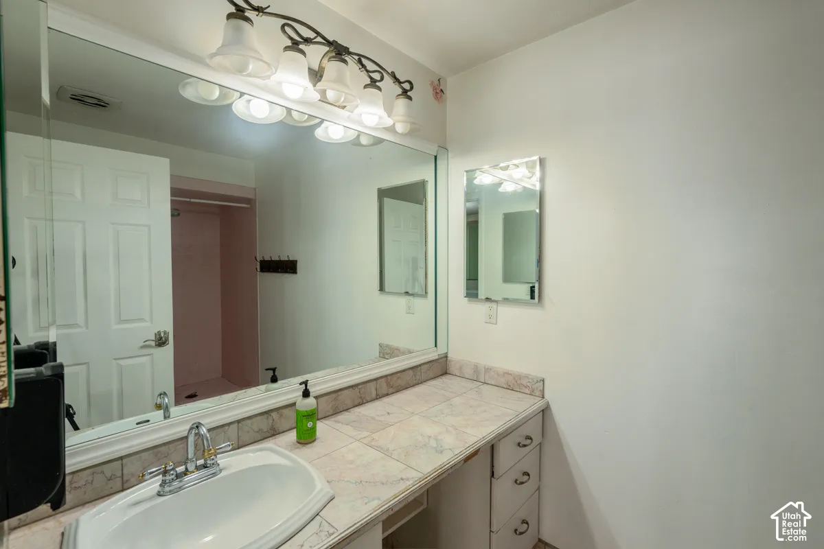 Vanity with a drop-in sink, chrome faucet, tiled countertop, and built-in drawers