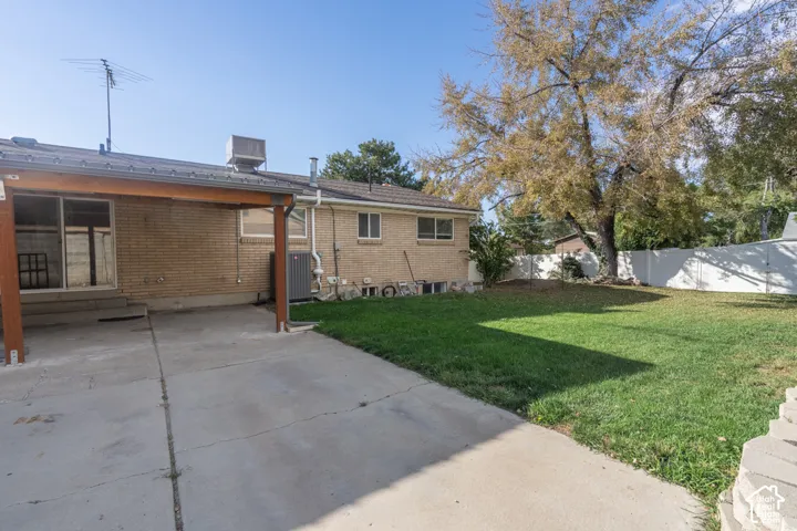 Brick exterior with covered patio, concrete patio, concrete pathways, and a grassy lawn