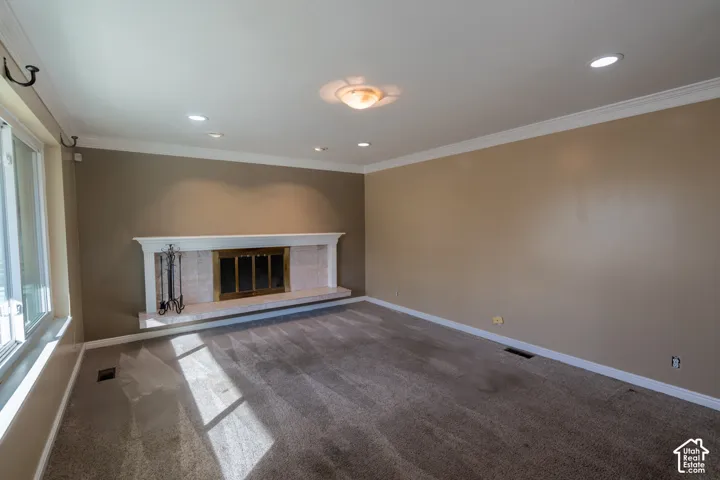 Carpeted room featuring a white mantel fireplace, recessed lighting, and crown molding