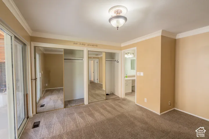 Crown molding, ceiling-mounted light fixture, sliding glass door, mirrored closet doors, and plush carpeting
