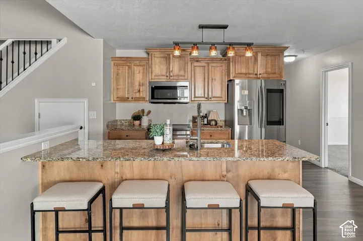 Kitchen island with a granite countertop, undermount sink, and wood-finish cabinetry