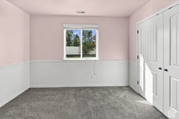 Carpeted interior space featuring white wainscoting, a single window, and a pair of paneled doors