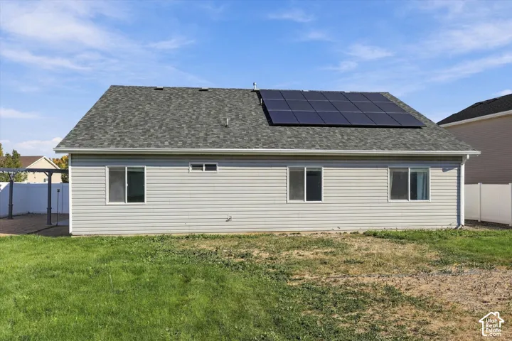 SOLAR PANELS are paid off.  Gable roof with asphalt shingles, solar panel array, horizontal vinyl siding, and a paved patio area