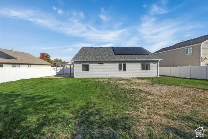 Big blue skies, rear exterior featuring solar panels, light gray siding, white vinyl fencing, a concrete patio, and a covered pergola structure
