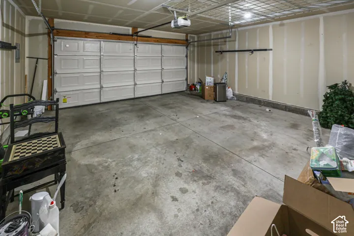 Spacious garage featuring a concrete floor, overhead lighting, and a white paneled garage door
