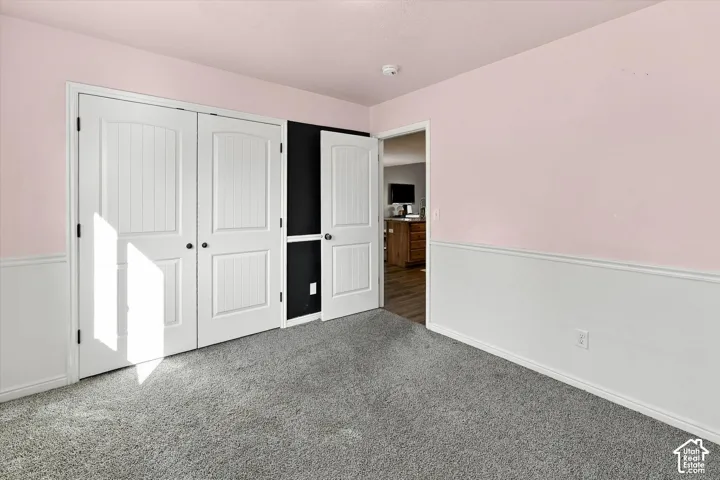 Carpeted flooring, white wainscoting, solid panel interior doors, and a ceiling-mounted smoke detector