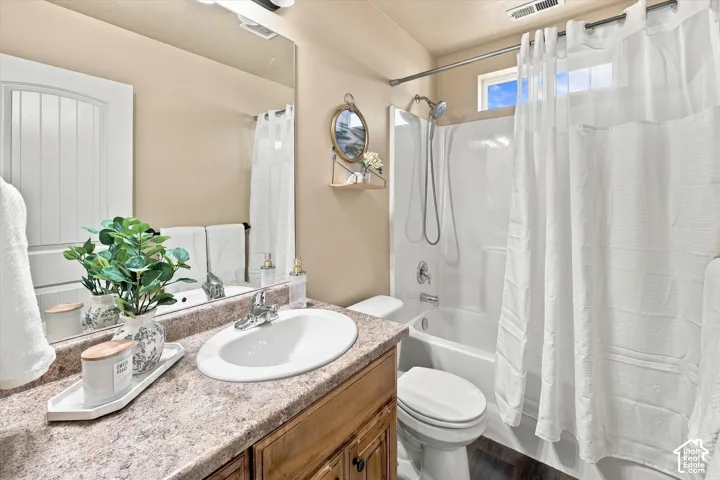 Bathroom featuring a vanity with an integrated sink, a full-width mirror, a shower-tub combination, and a high window