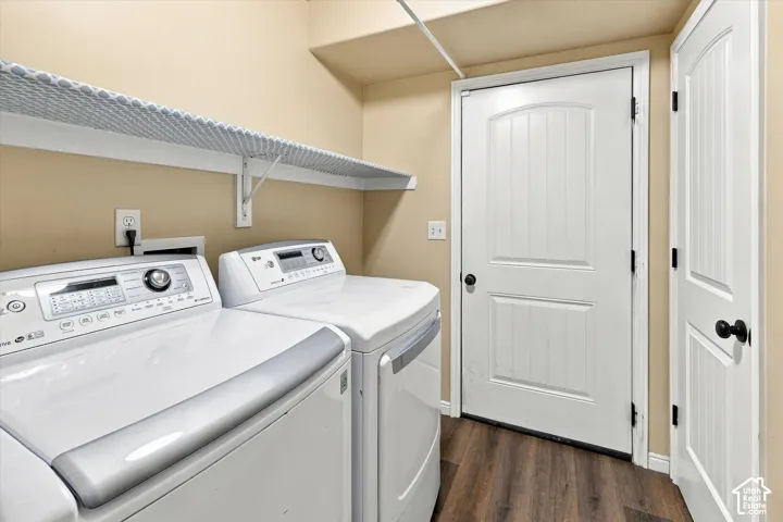 Laundry area featuring a built-in storage shelf, wood-finish flooring, storage room, and door to garage