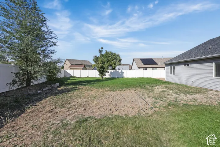 Expansive yard space with established trees and a privacy fence