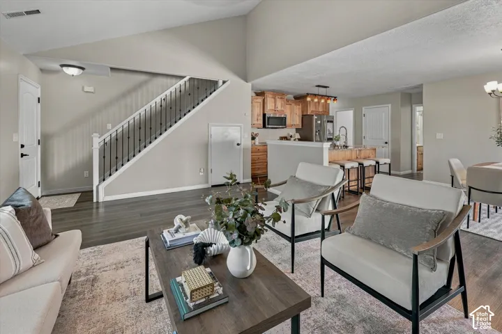 Vaulted ceiling, wood-finish flooring, staircase with metal balusters, natural wood cabinetry, and stainless steel appliances