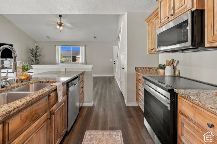 Kitchen featuring wood cabinetry, granite-style countertops, stainless steel appliances, and wood-finish flooring