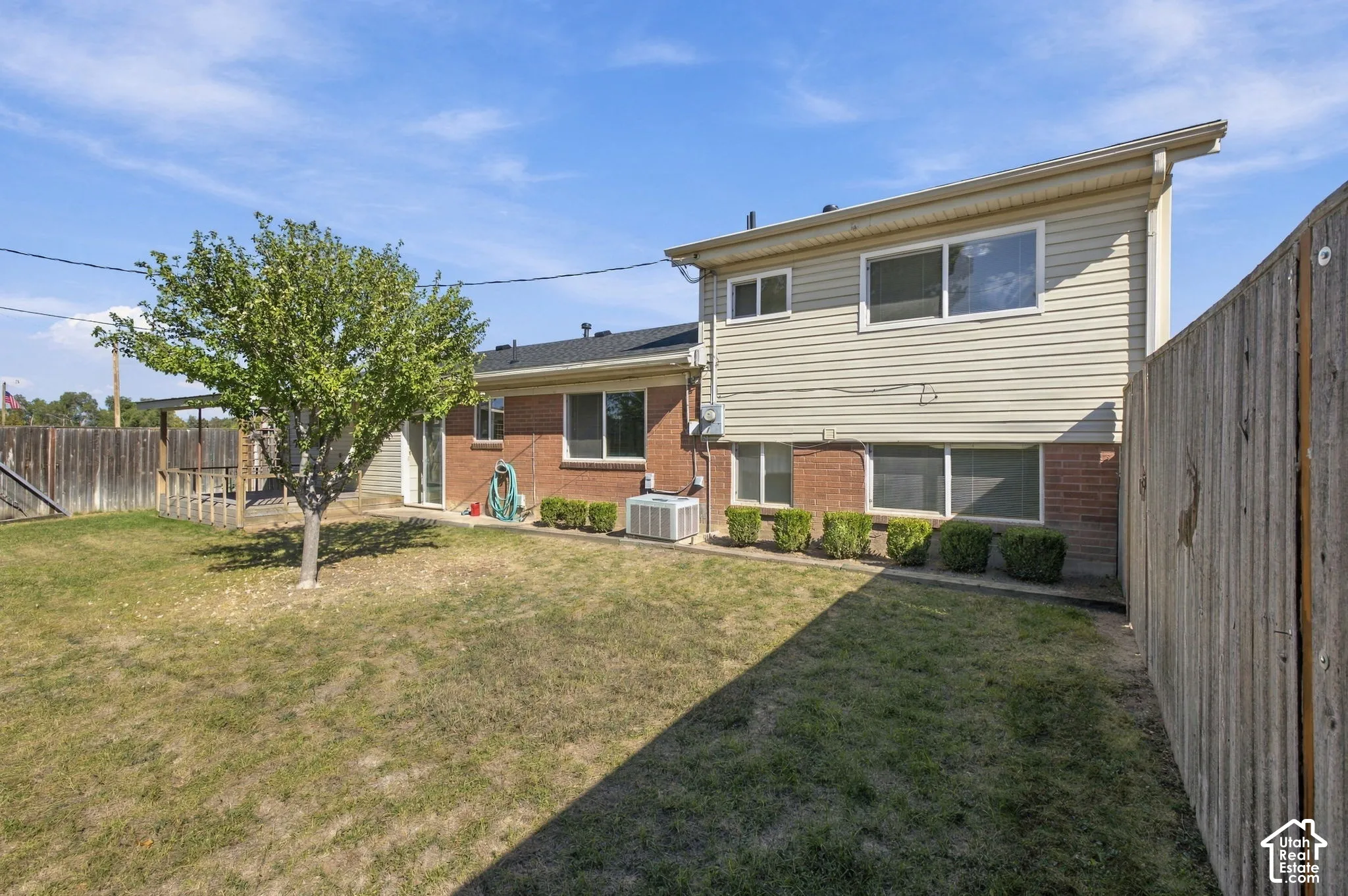 Expansive backyard featuring a mature tree, private fencing, and a multi-story exterior with brick and siding finishes
