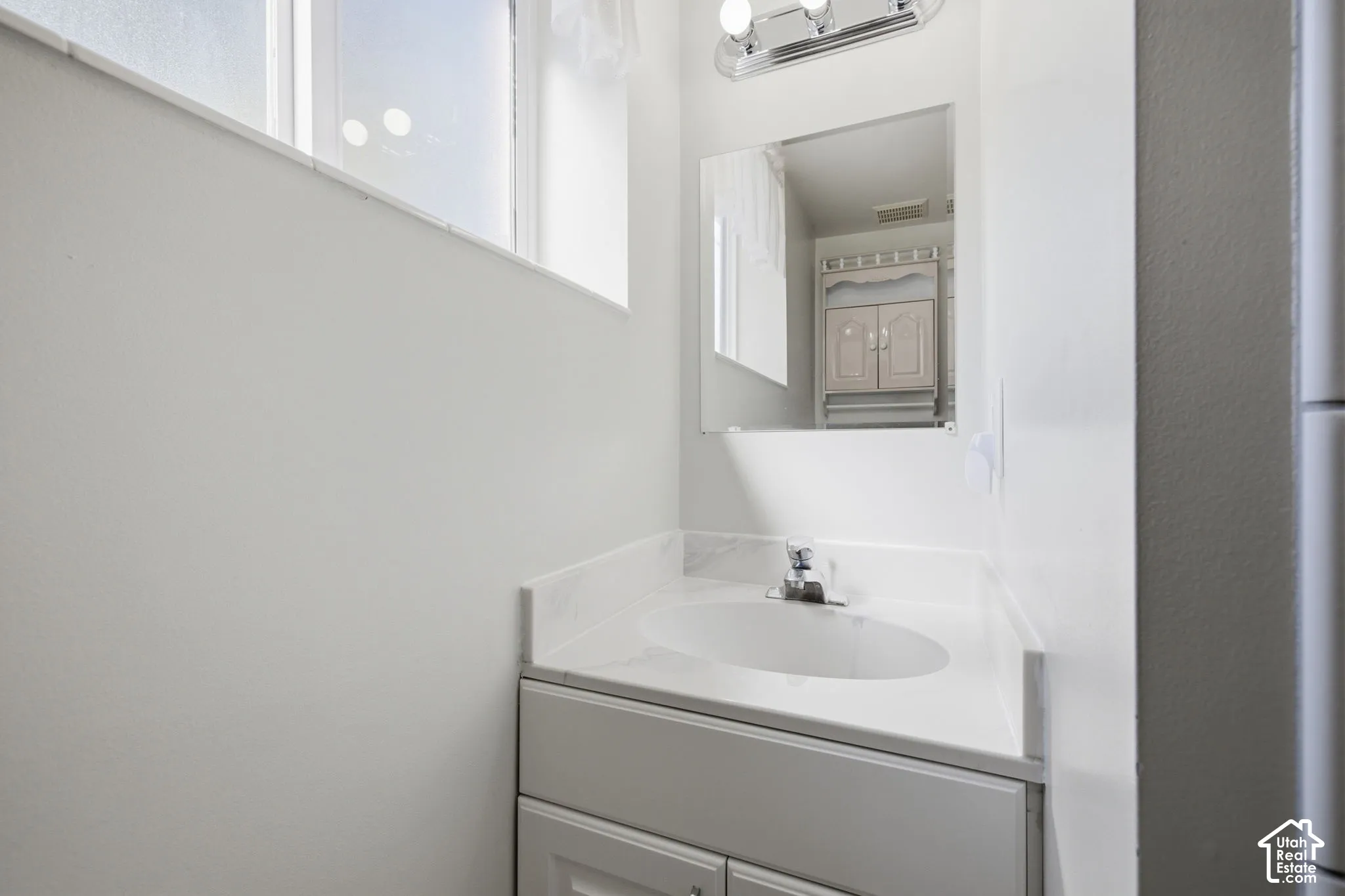 Vanity with an integrated sink, polished chrome faucet, and under-cabinet storage