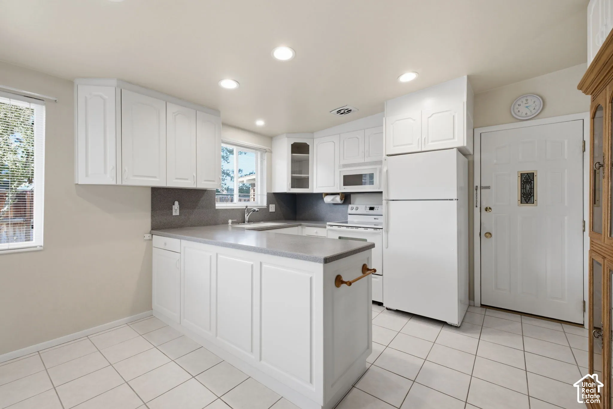 White cabinetry, recessed lighting, tile flooring, and integrated white appliances