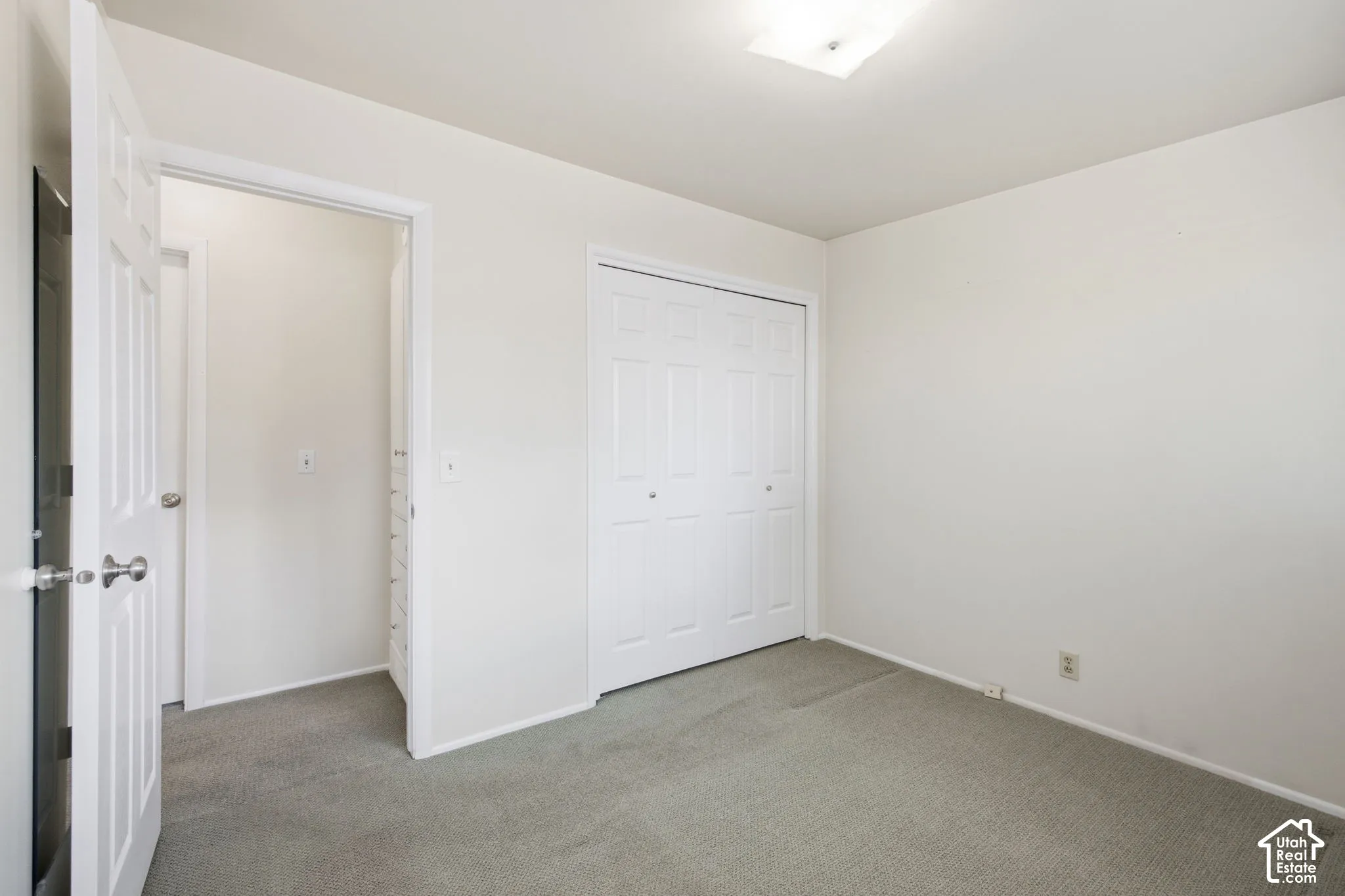 Neutral wall finishes with a ceiling-mounted light fixture, and a built-in closet with bifold doors