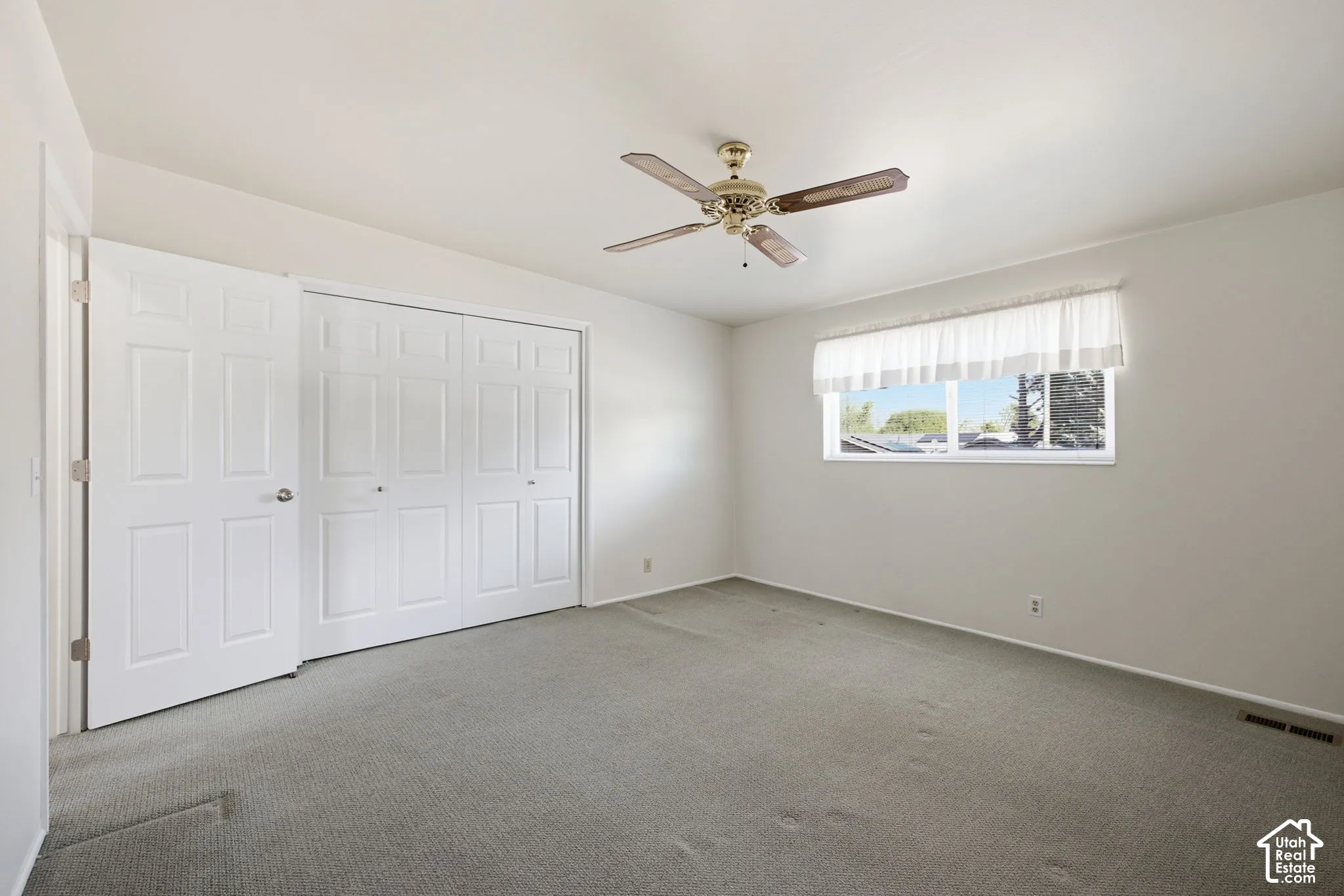 Room featuring a ceiling fan, window with natural light, and bi-fold closet doors