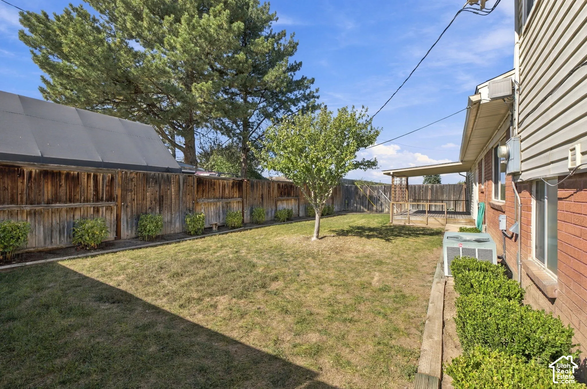Expansive backyard featuring a covered patio, wood fencing, and mature trees