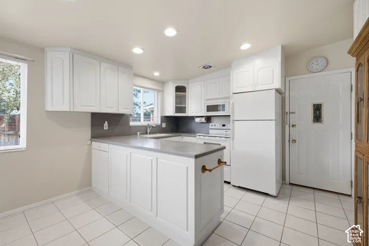 White cabinetry, recessed lighting, tile flooring, and integrated white appliances