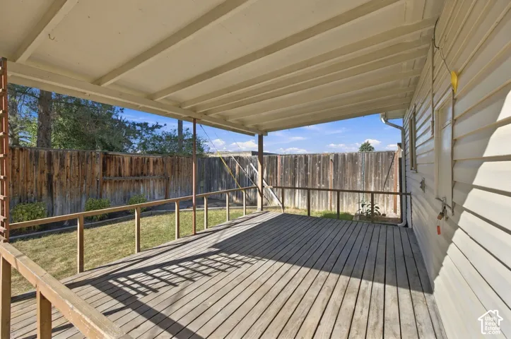 Expansive covered deck with wood flooring and wood railing