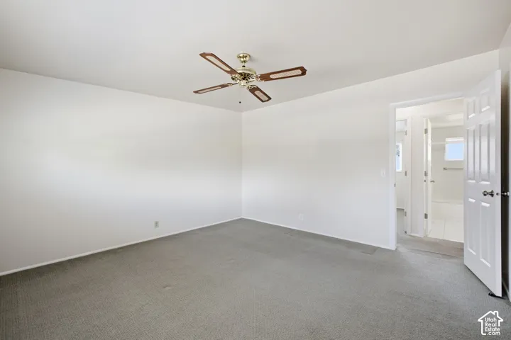 Spacious room featuring ceiling fan with integrated lighting, neutral carpet flooring, and a white paneled door