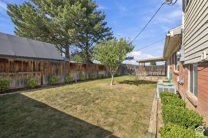 Expansive backyard featuring a covered patio, wood fencing, and mature trees