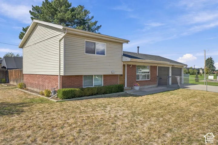 Brick and siding exterior with a two-car garage, mature landscaping, and a fenced area