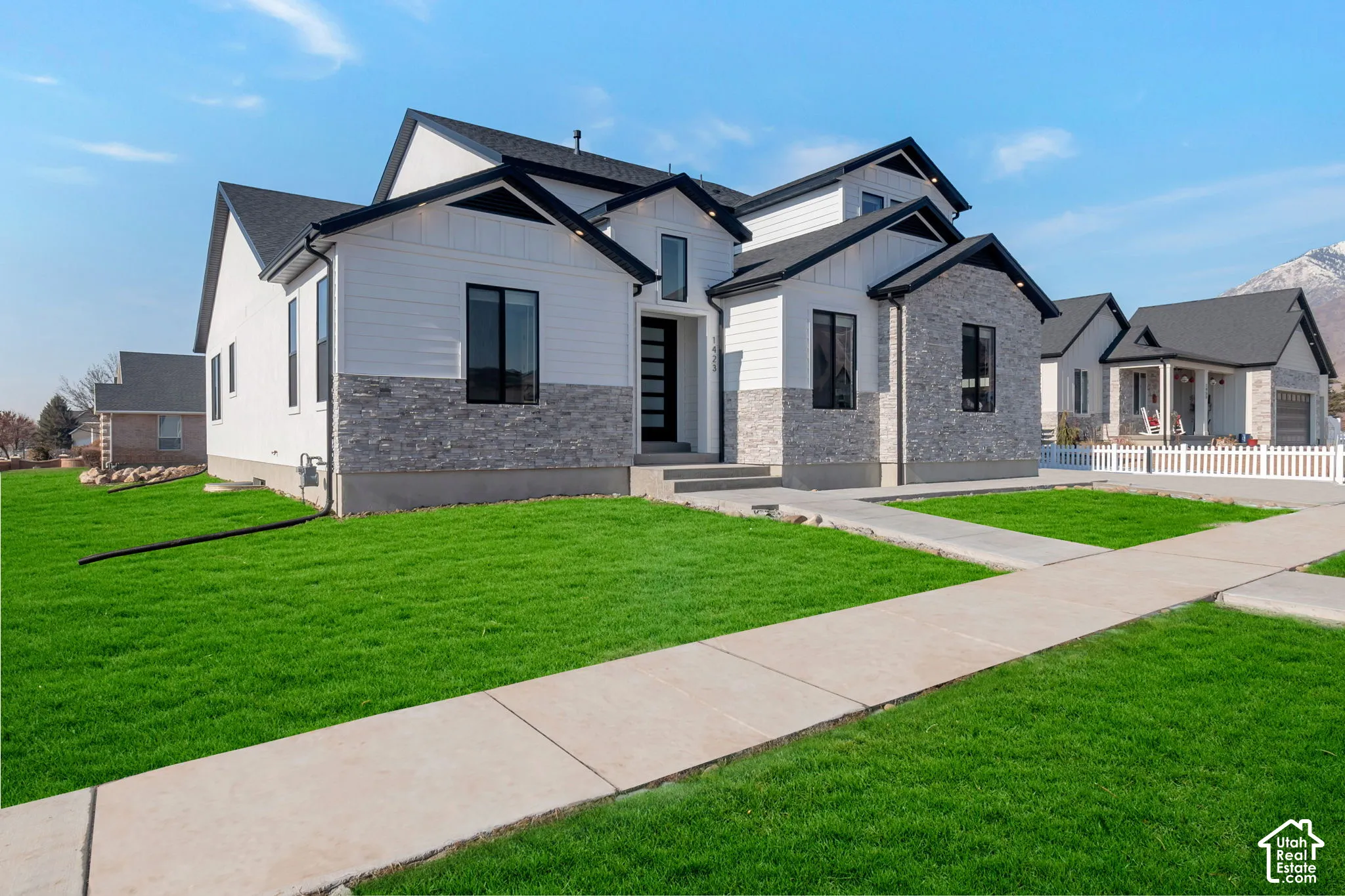 Contemporary-style residence with dark asphalt shingle roofing, white siding, and light grey stone veneer accents