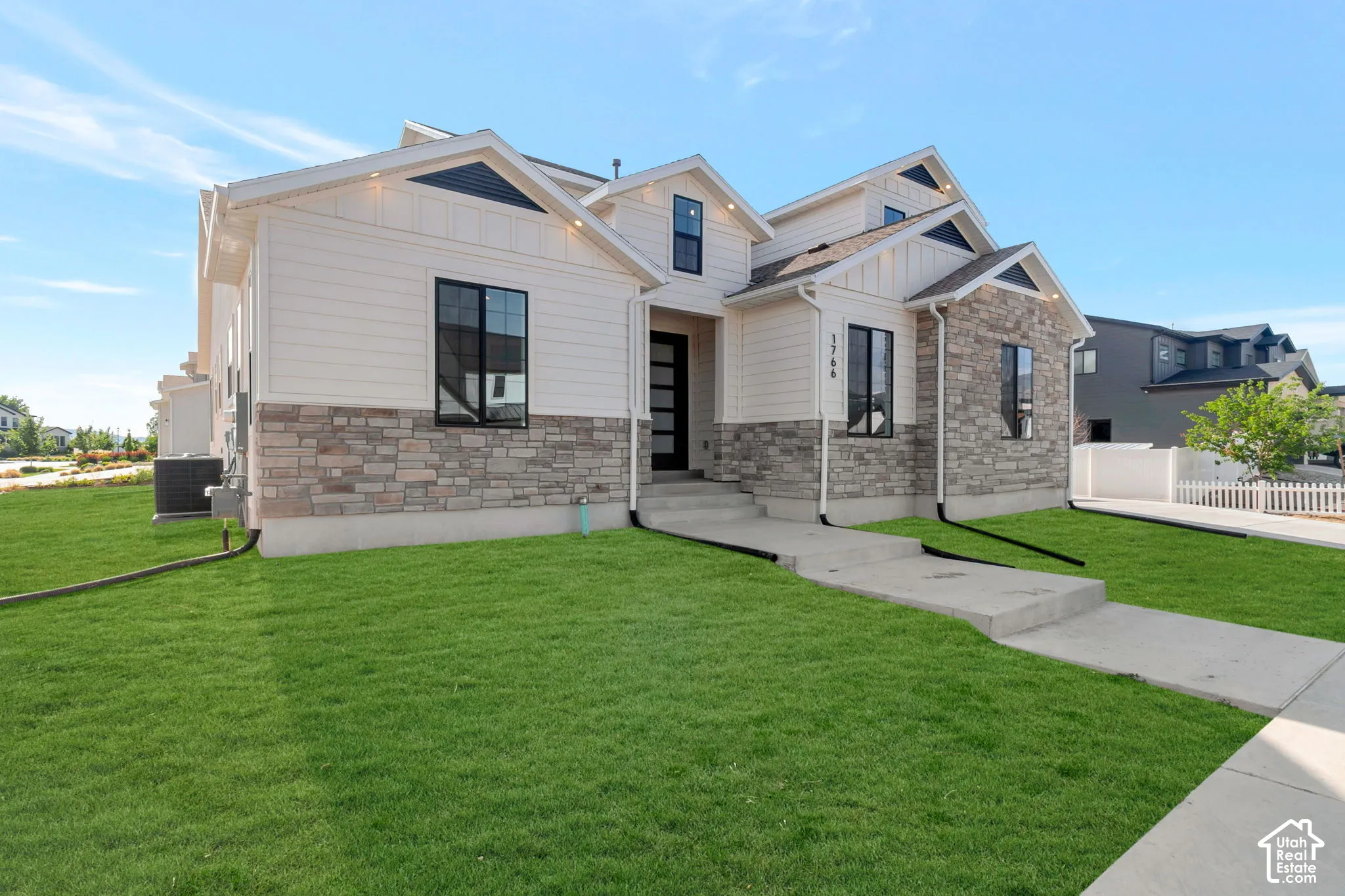 Modern-style exterior featuring a stone and siding facade, black-trimmed windows, and a concrete pathway