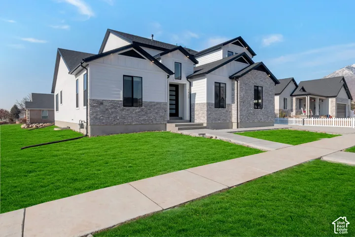 Contemporary-style residence with dark asphalt shingle roofing, white siding, and light grey stone veneer accents