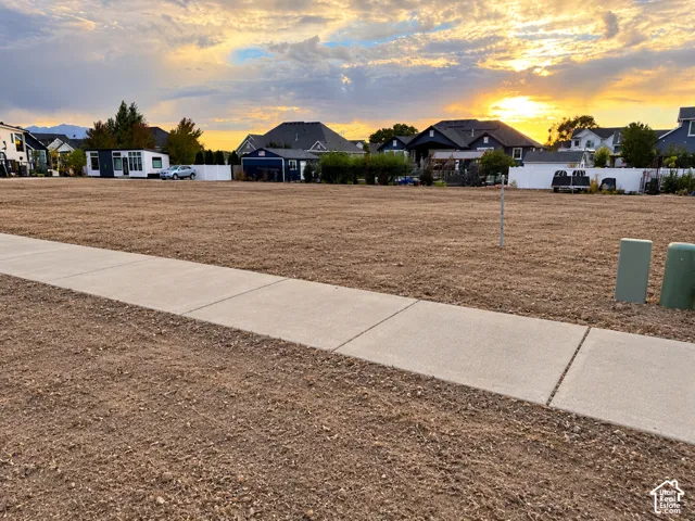 Expansive undeveloped lot with a level grade, concrete sidewalk, and utility boxes