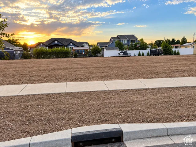 Expansive land parcel with a prepared surface for development, featuring an established curb and sidewalk