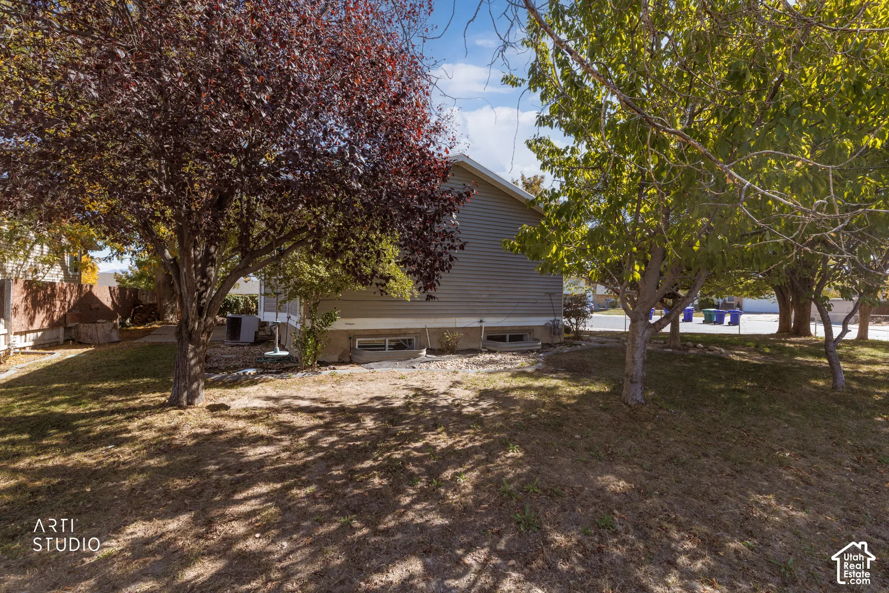 Side exterior with horizontal siding, mature trees, and a sloped lawn