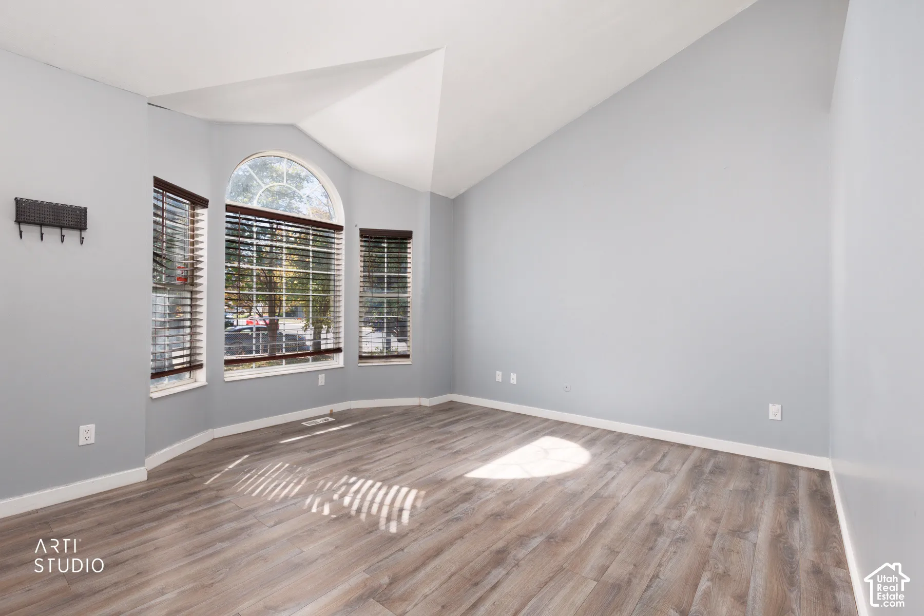 Vaulted ceiling with wood-finish flooring, featuring a bay window with an arched transom