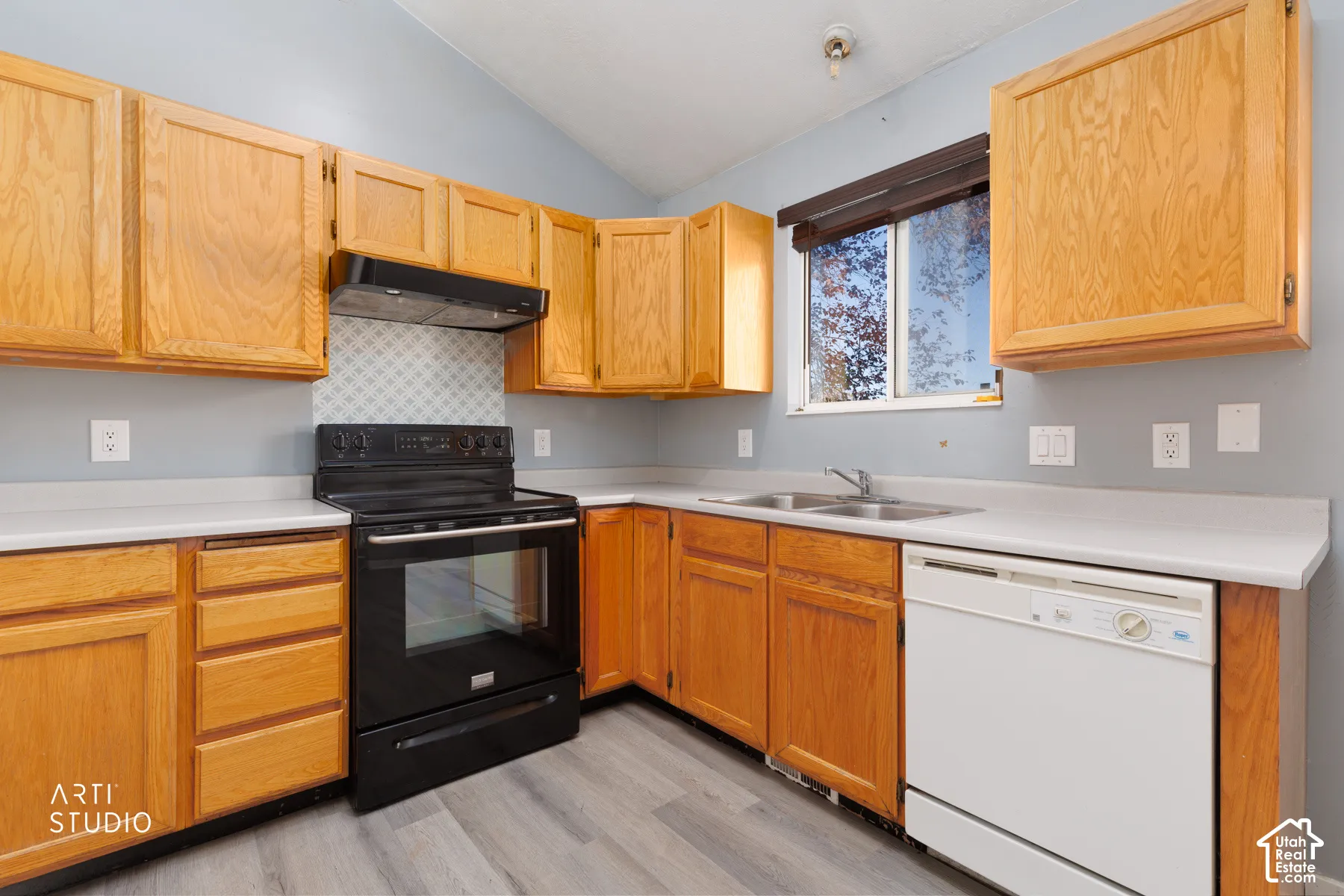 Kitchen featuring wood cabinetry, white countertops, a black range with hood, a double basin stainless steel sink, and a white dishwasher