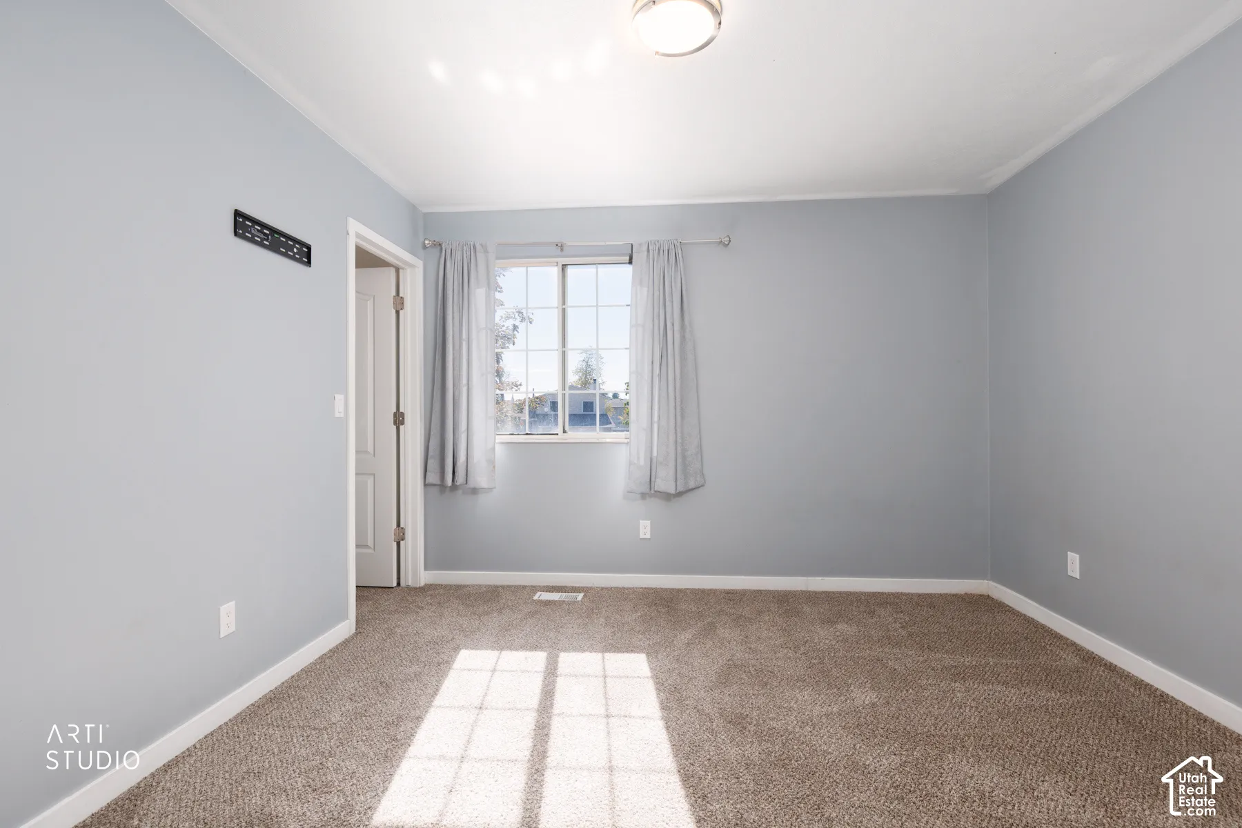 Window with grid pattern, neutral gray walls, crown molding, and plush carpet flooring