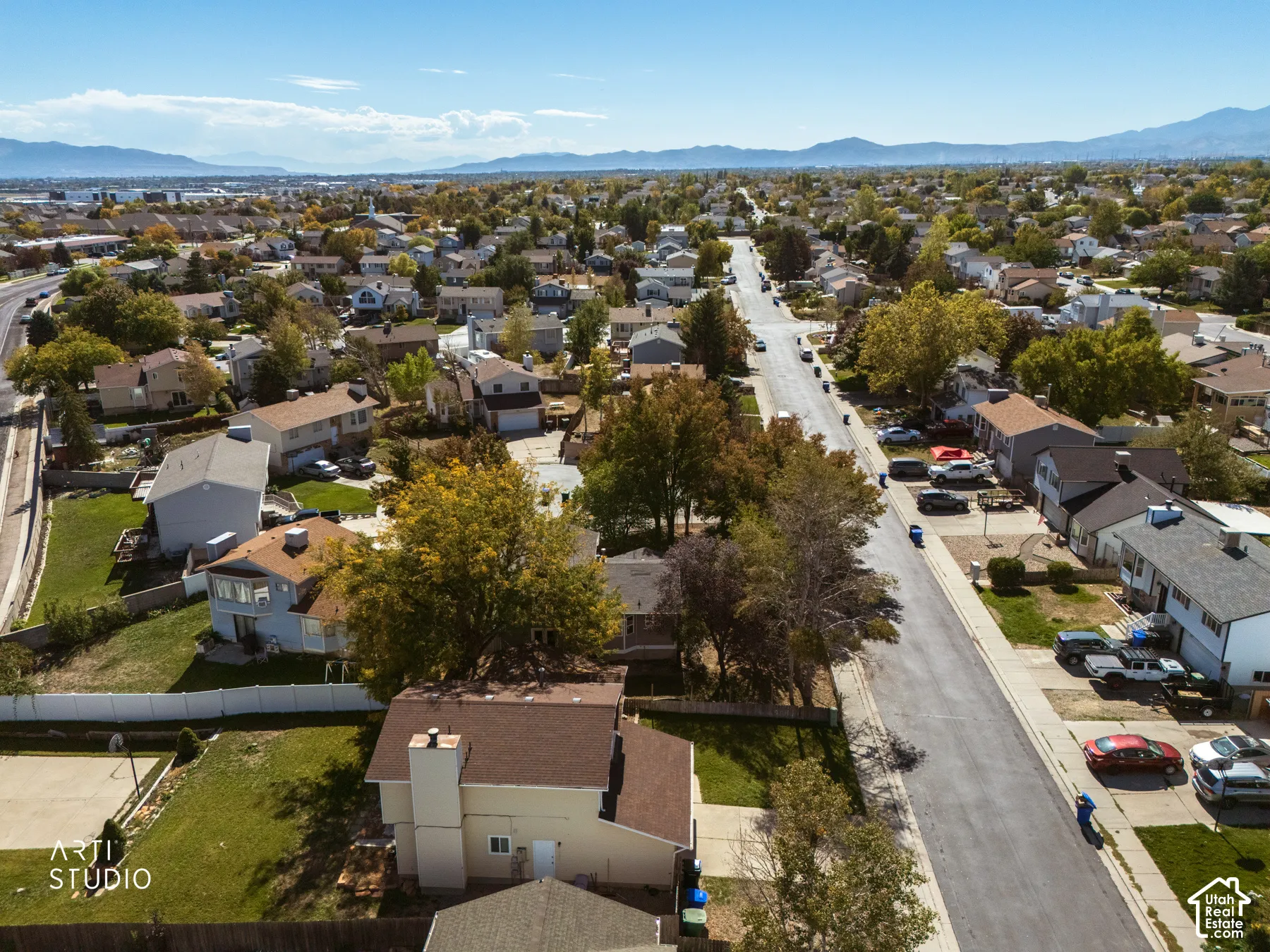 Residential street with established homes, mature trees, and distant mountains