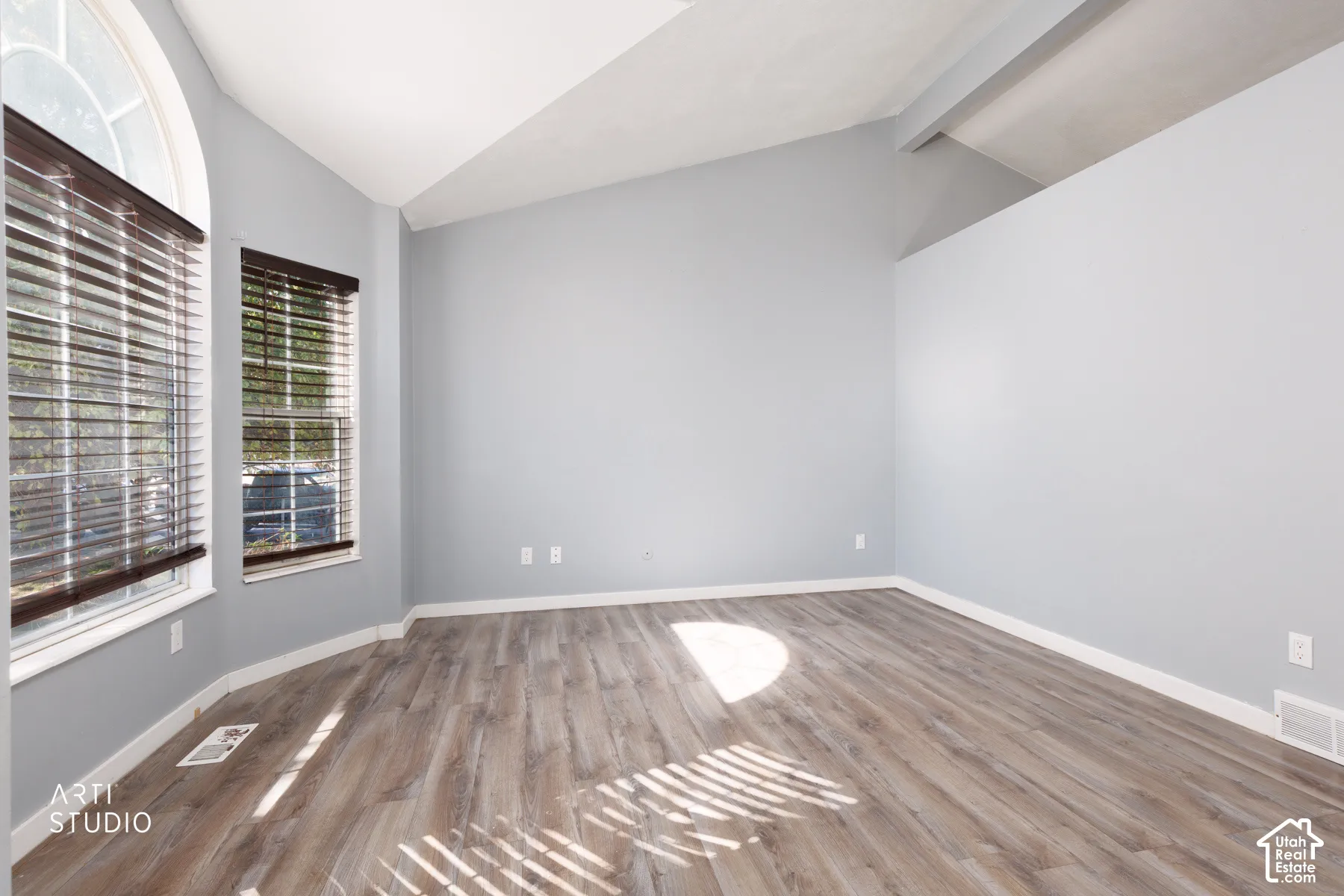 Vaulted ceilings, wood-finish flooring, and multiple windows with blinds
