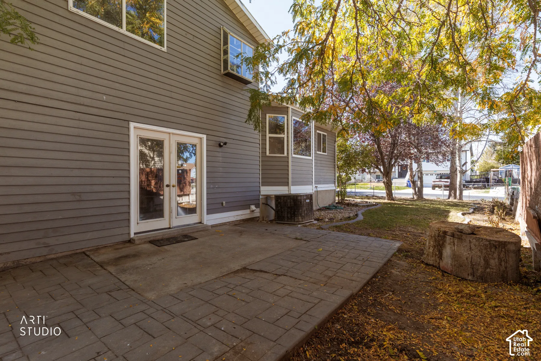 Patio with paver and concrete surfaces, double glass-paneled doors, and exterior siding