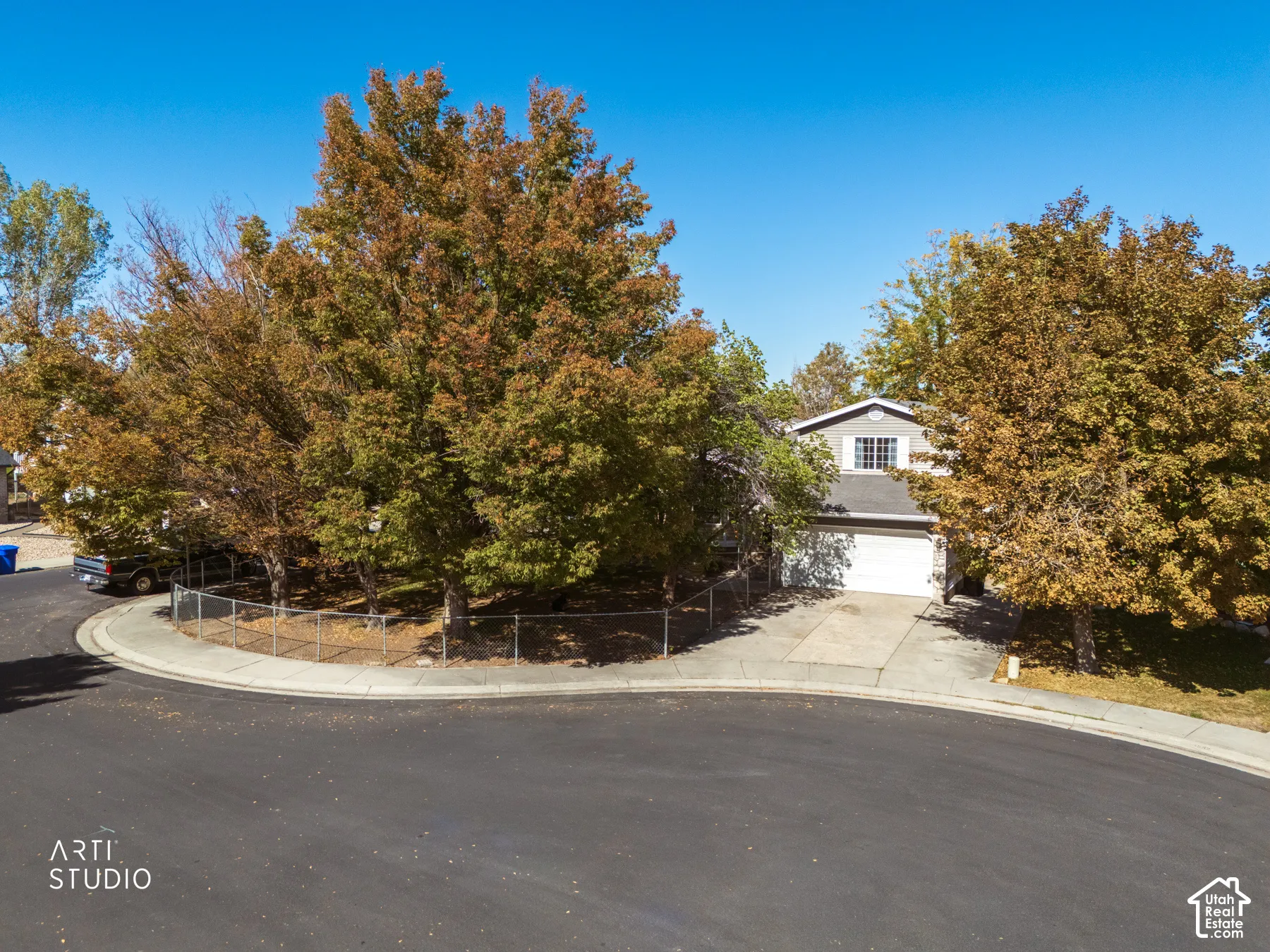 Two-story residence featuring a two-car garage, dormer window, and mature trees