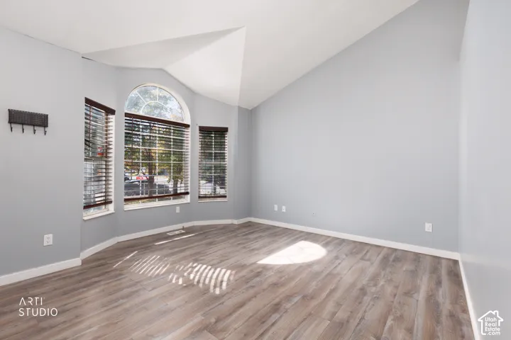 Vaulted ceiling with wood-finish flooring, featuring a bay window with an arched transom