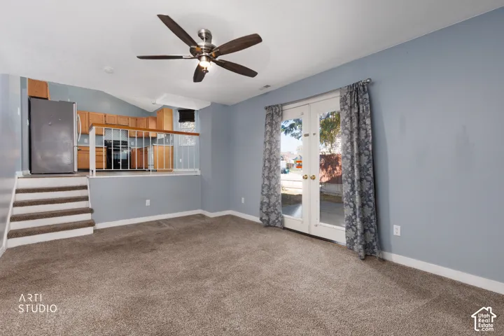 Carpeted living area with a vaulted ceiling and ceiling fan