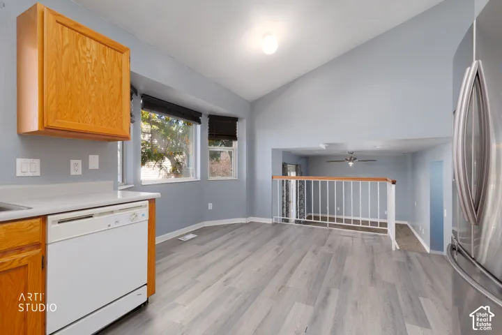 Kitchen area featuring light wood cabinetry, a white dishwasher, light countertop, and wood-finish flooring