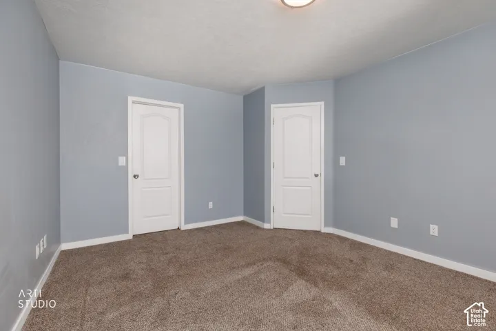 Textured carpeting, two paneled doors, light blue wall paint, and white trim
