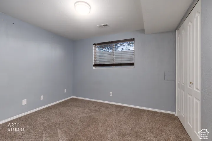 Carpeted room with light blue walls, a ceiling-mounted light fixture, and a window with horizontal blinds