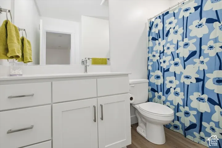 White vanity with brushed nickel hardware, integrated sink, chrome faucet, and wood-finish flooring