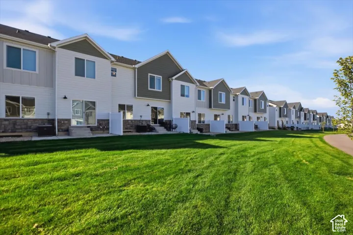 Row of modern townhomes with white and gray siding, stone accents, private patios, and sliding glass doors