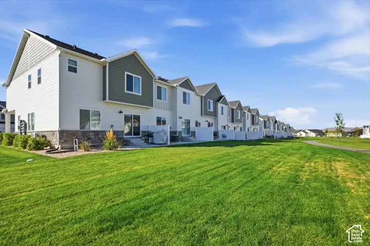 Townhome exterior featuring white siding, green-gray gables, a stone facade, and a private patio
