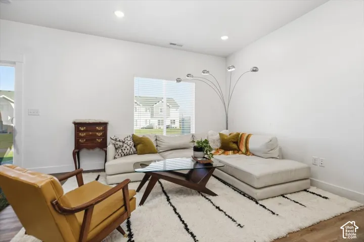 Recessed lighting, wood-finish flooring, and a large window with blinds