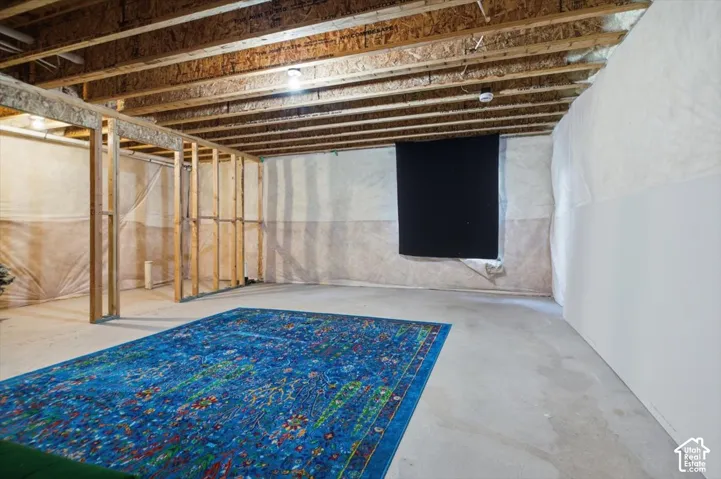 Unfinished basement featuring exposed wood joists and concrete flooring