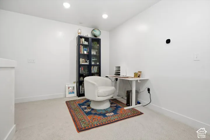 Recessed ceiling lighting, light-colored carpeting, white wall finishes, and a built-in display cabinet